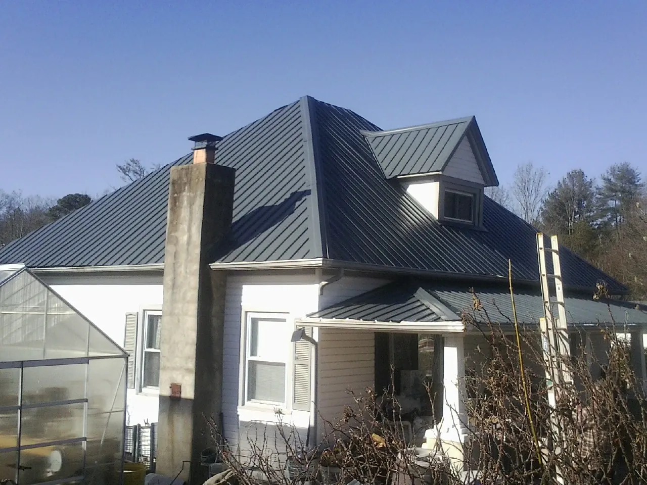 Dark blue standing seam metal roof on a white farmhouse with dormer — Slate & Tile Roof Repair by Roofing Brothers in Millburn