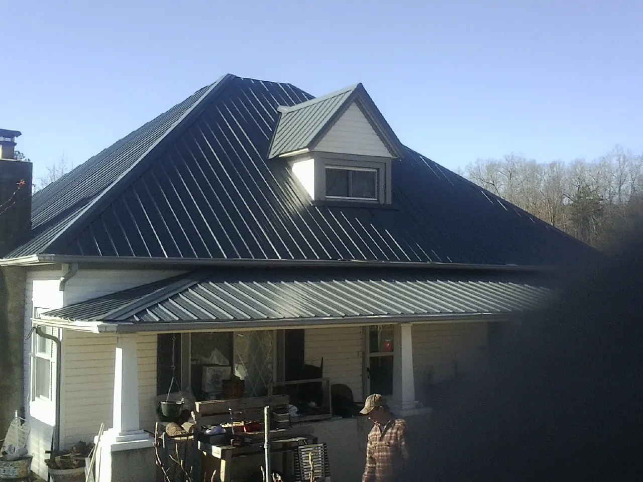 Dark blue standing seam metal roof with a dormer above a front porch in Millburn