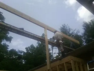 Carpenter setting a ridge beam over a new addition frame — Ice Dam Removal by Roofing Brothers in Millburn