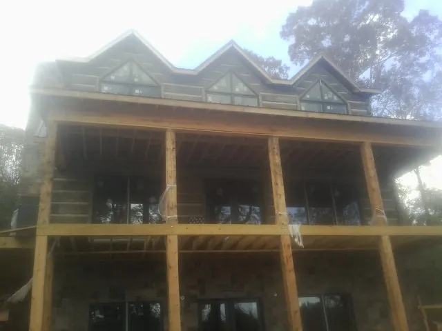 Dormers and porch framing on a large log home under construction — Roof Coating work by our crew in Millburn