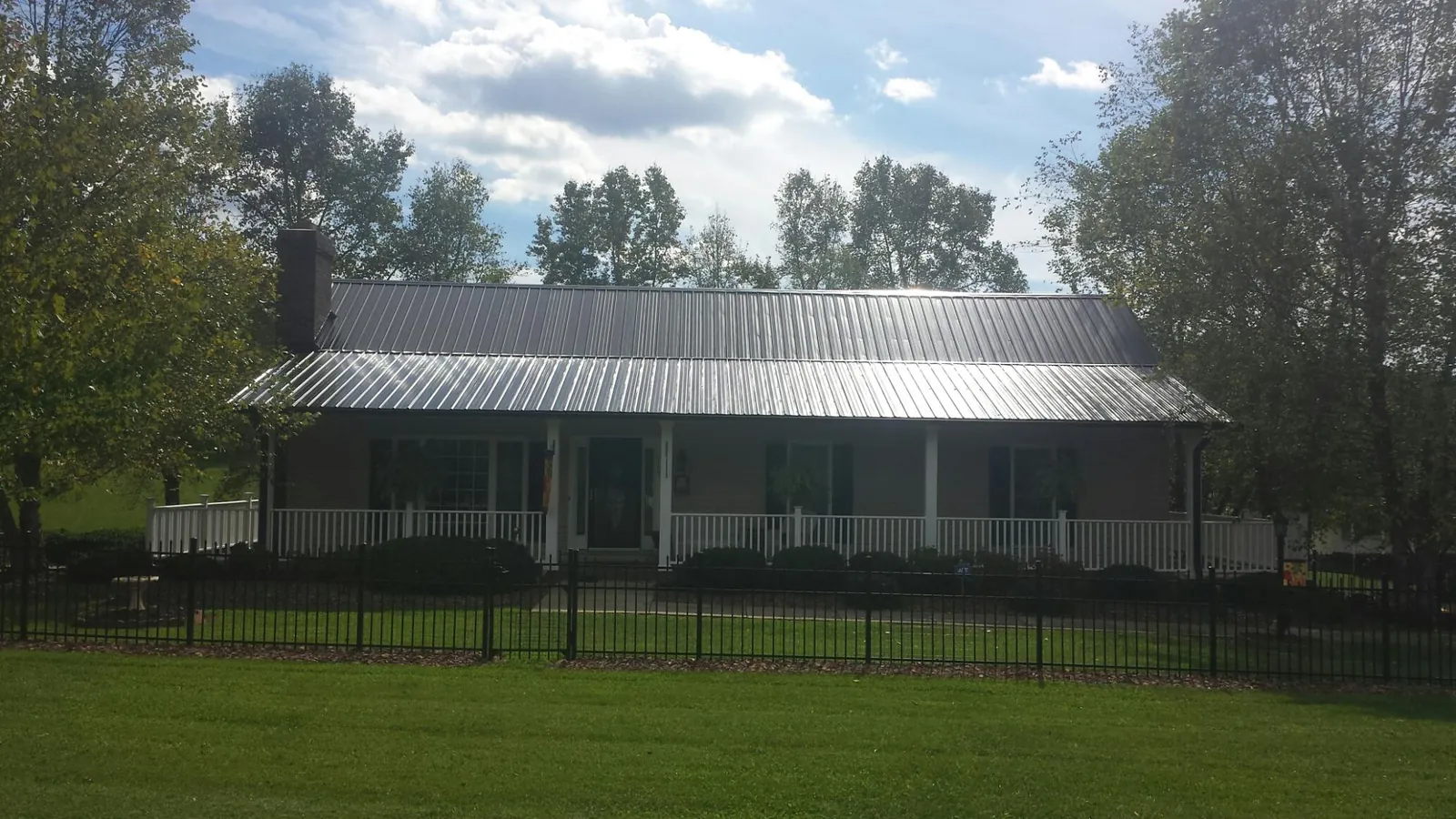 Gray metal roof on a brick ranch with a full width front porch — Gutter Guard Installation work by our crew in Millburn