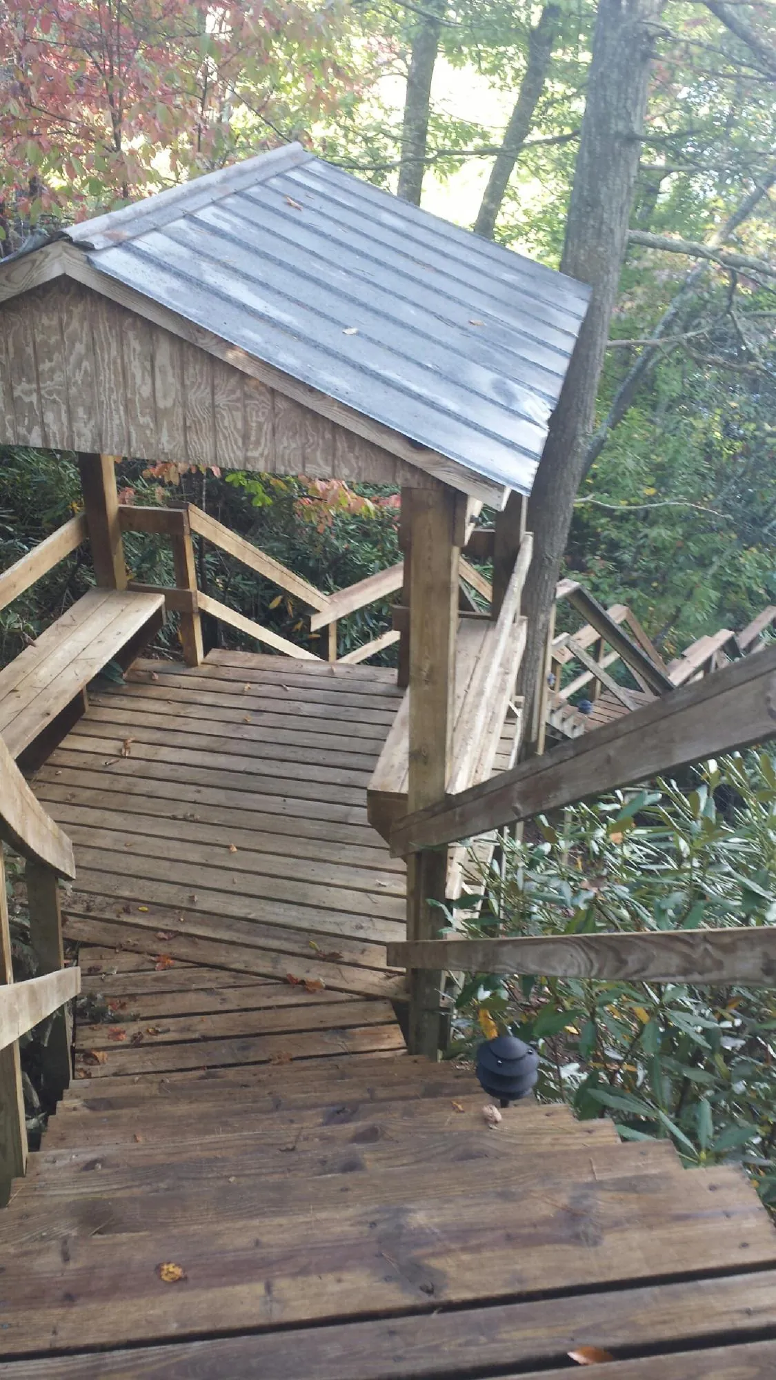 Metal roofed shelter over wooden steps on a wooded walkway — Skylight Repair & Installation work by our crew in Millburn