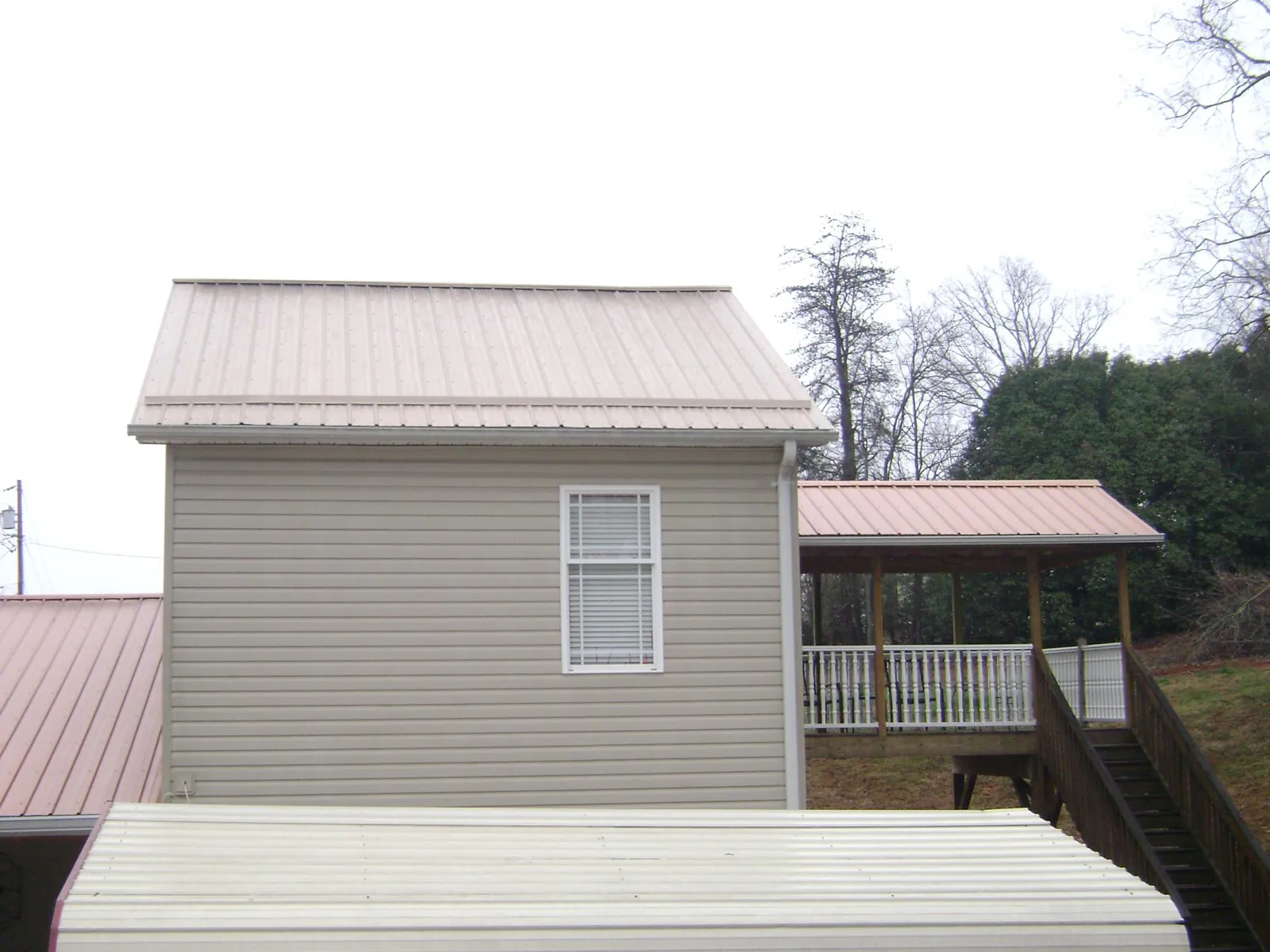Tan metal roofs on a two story addition and attached porch, from a Roof Replacement job in Millburn