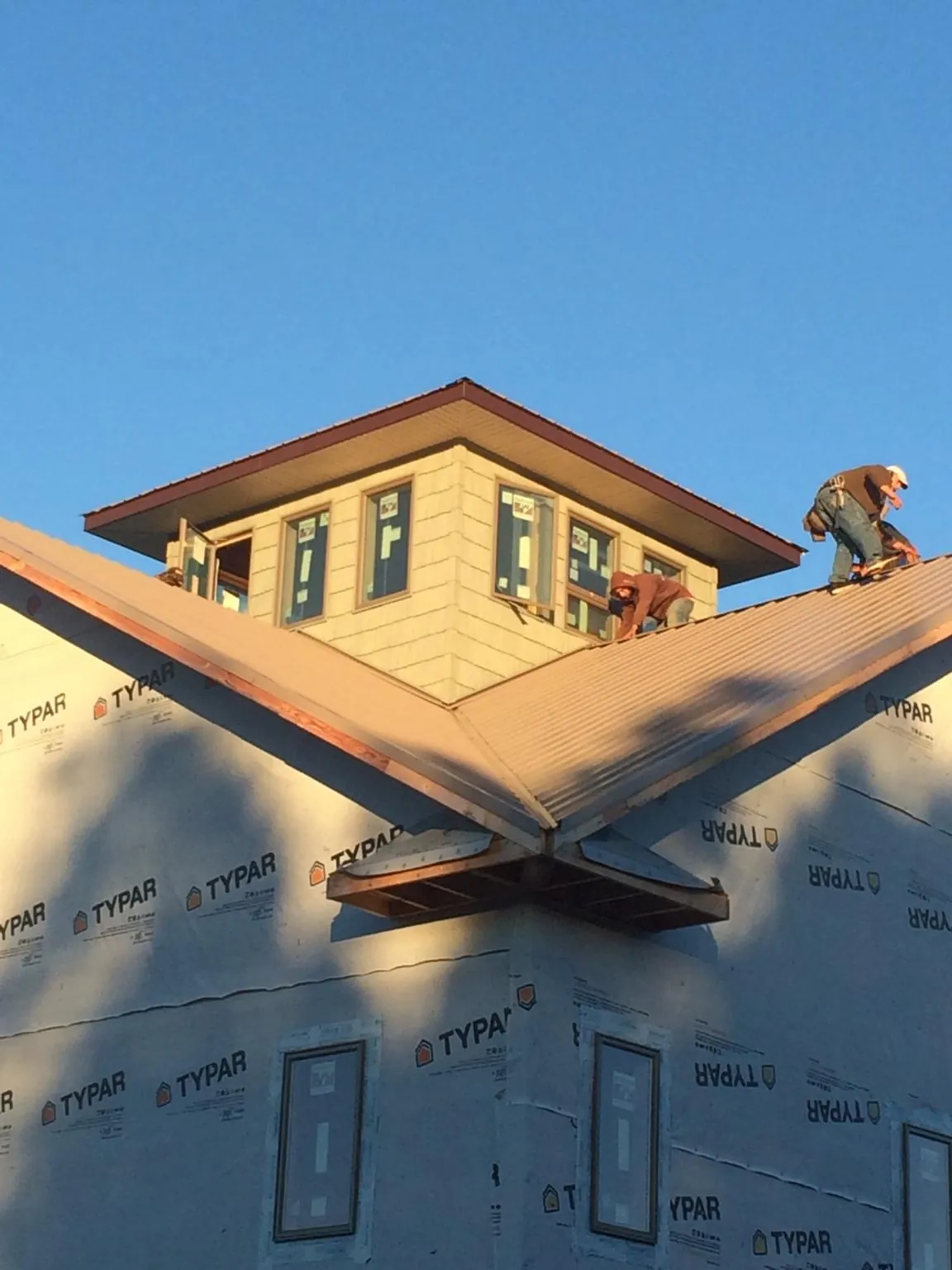 Roofers working around a rooftop cupola on a new metal roof at sunset — Roof Waterproofing in Millburn by Roofing Brothers